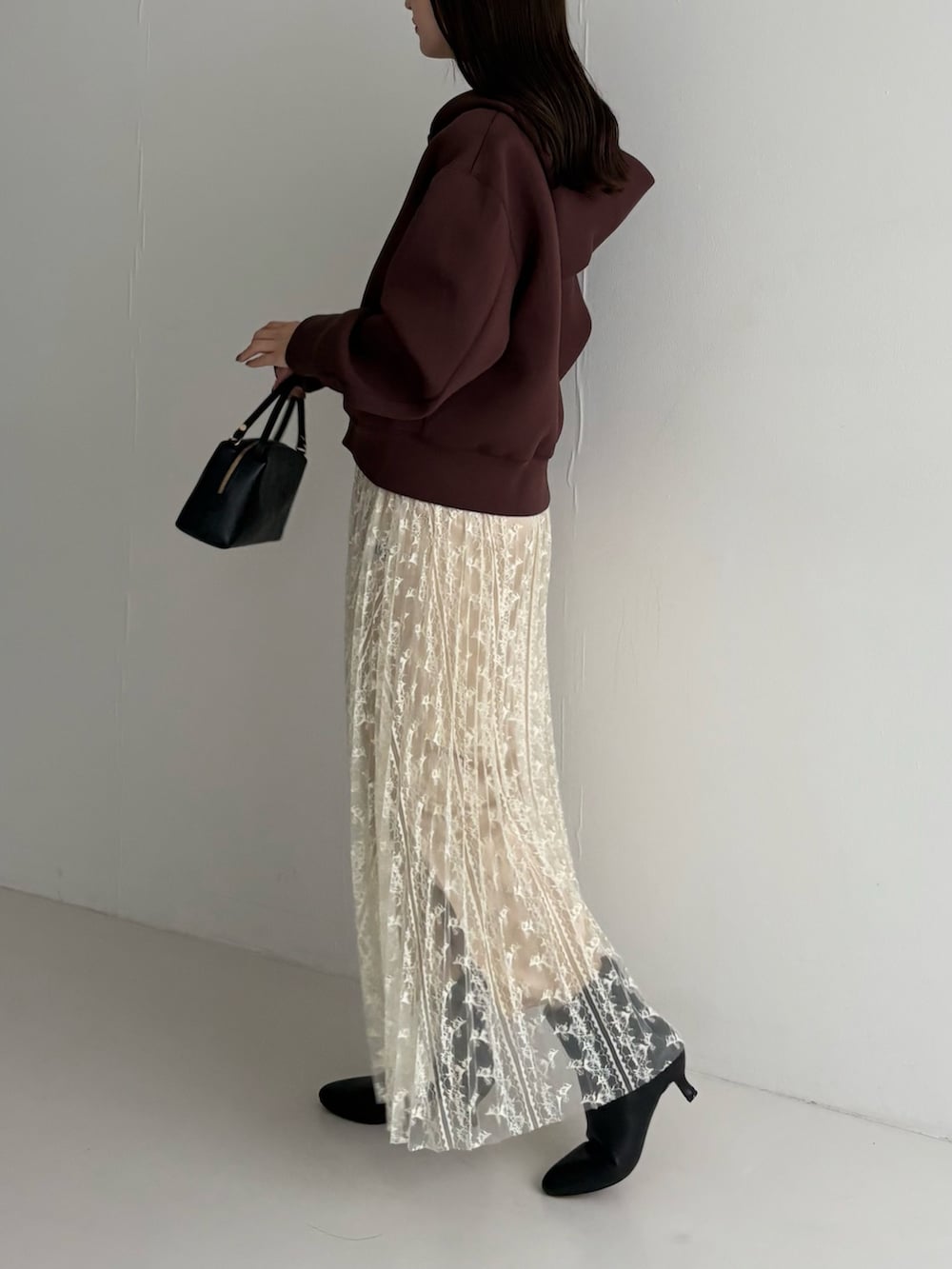 ホワイト系のスカート、ブラック系のブーツ、ブラウン系のパーカーを着用したレディースの秋コーディネートの2枚目の写真