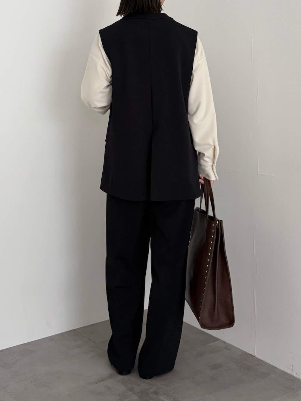 ブラック系のベスト、ホワイト系のシャツ/ブラウス、ブラック系のその他パンツを着用したレディースの冬コーディネートの3枚目の写真