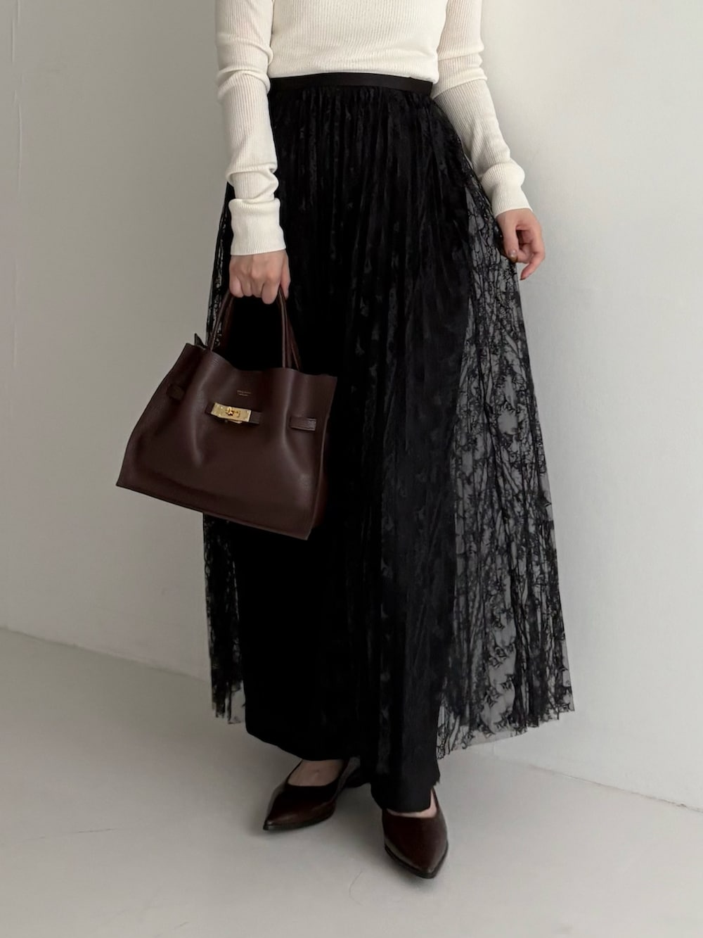 ホワイト系のニット/セーター、ブラック系のスカート、ブラック系のその他パンツを着用したレディースの秋コーディネートの2枚目の写真