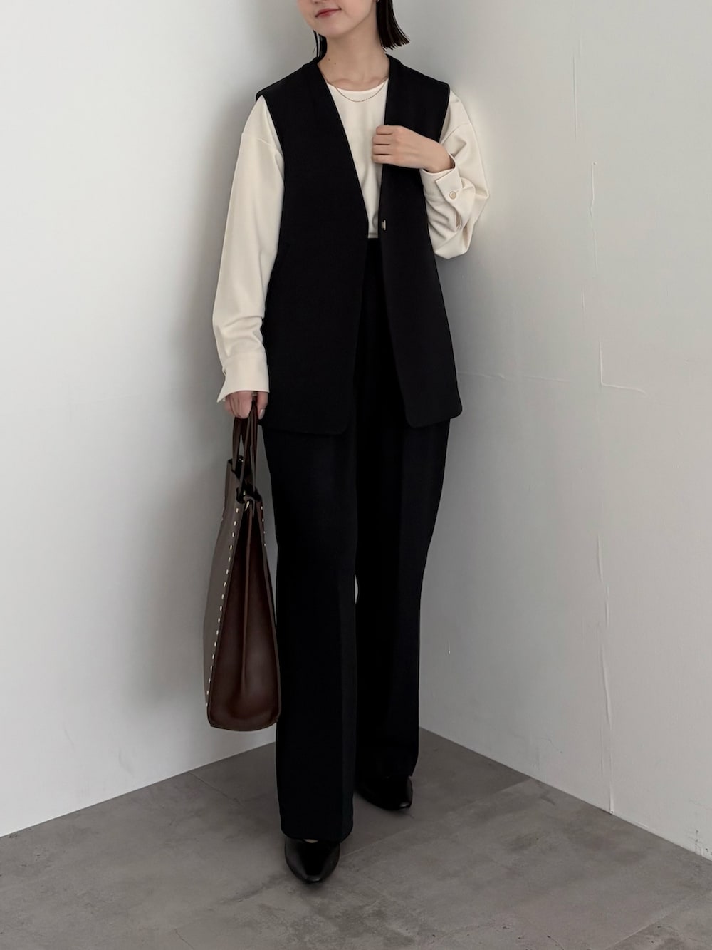 ブラック系のベスト、ホワイト系のシャツ/ブラウス、ブラック系のその他パンツを着用したレディースの冬コーディネートの2枚目の写真