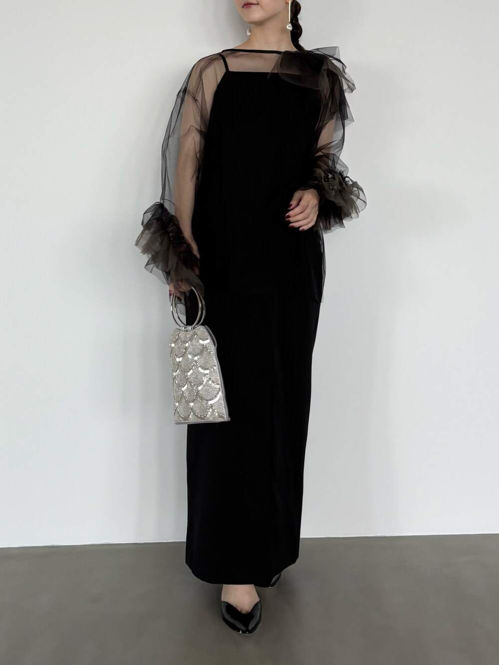 シルバー系のハンドバッグ、ブラック系のワンピースを着用したレディースの秋コーディネートの3枚目の写真