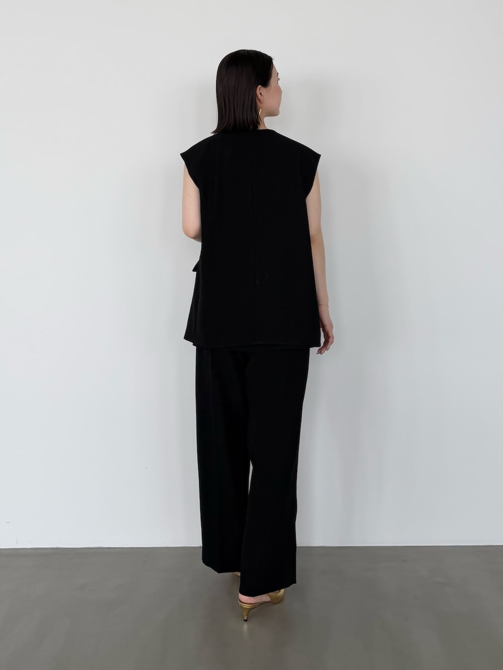 ブラック系のセットアップ、ゴールド系のパンプスを着用したレディースの春コーディネートの3枚目の写真