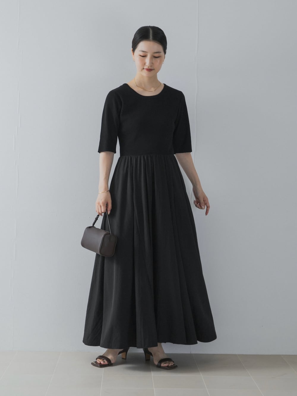 ブラック系のワンピース、ブラウン系のサンダル、ブラウン系のハンドバッグを着用したレディースの夏コーディネートの2枚目の写真