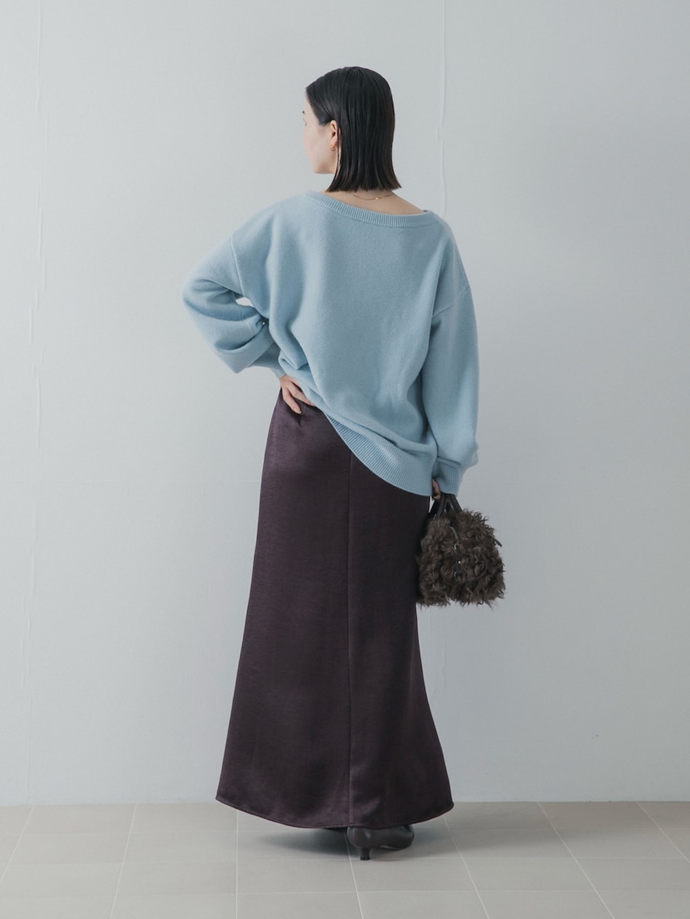 ブルー系のニット/セーター、ブラウン系のパンプス、ブラウン系のハンドバッグを着用したレディースの秋コーディネートの4枚目の写真