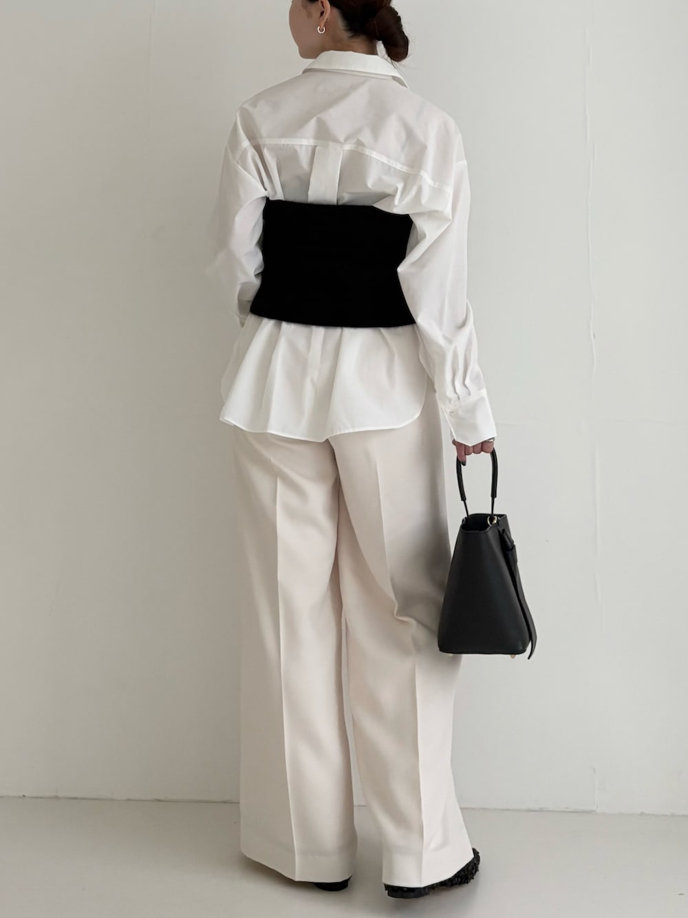 ブラック系のニット/セーター、ホワイト系のシャツ/ブラウス、ブラック系のハンドバッグを着用したレディースの秋コーディネートの3枚目の写真