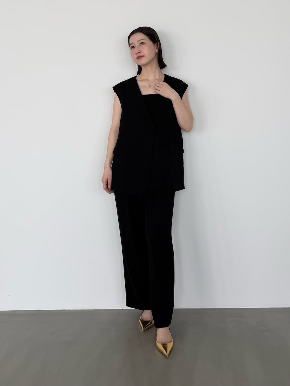 ブラック系のセットアップ、ゴールド系のパンプスを着用したレディースの春コーディネートの2枚目の写真