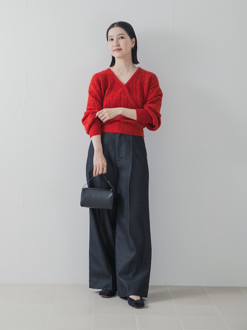 レッド系のニット/セーター、ブルー系のデニムパンツ、ブラック系のハンドバッグを着用したレディースの秋コーディネートの2枚目の写真