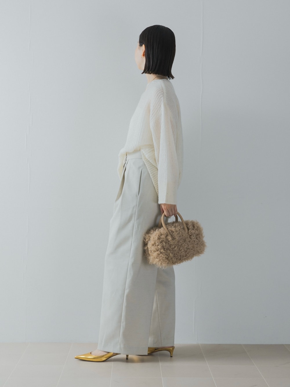 ホワイト系のニット/セーター、ゴールド系のパンプス、イエロー系のハンドバッグを着用したレディースの夏コーディネートの5枚目の写真