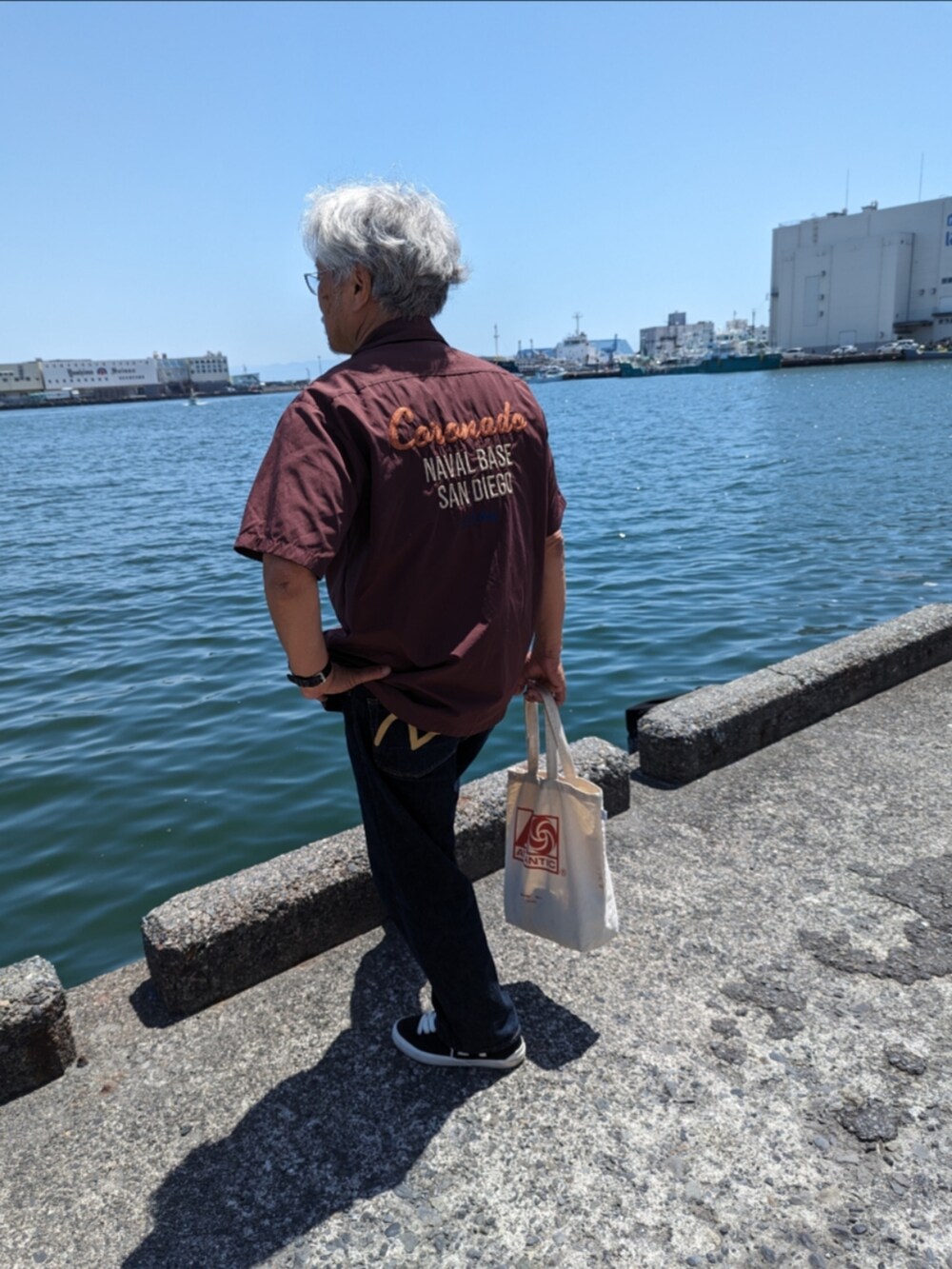 ブラウン系のシャツ/ブラウス、ブルー系のデニムパンツ、ブラック系のスニーカーを着用したメンズの春コーディネートの2枚目の写真