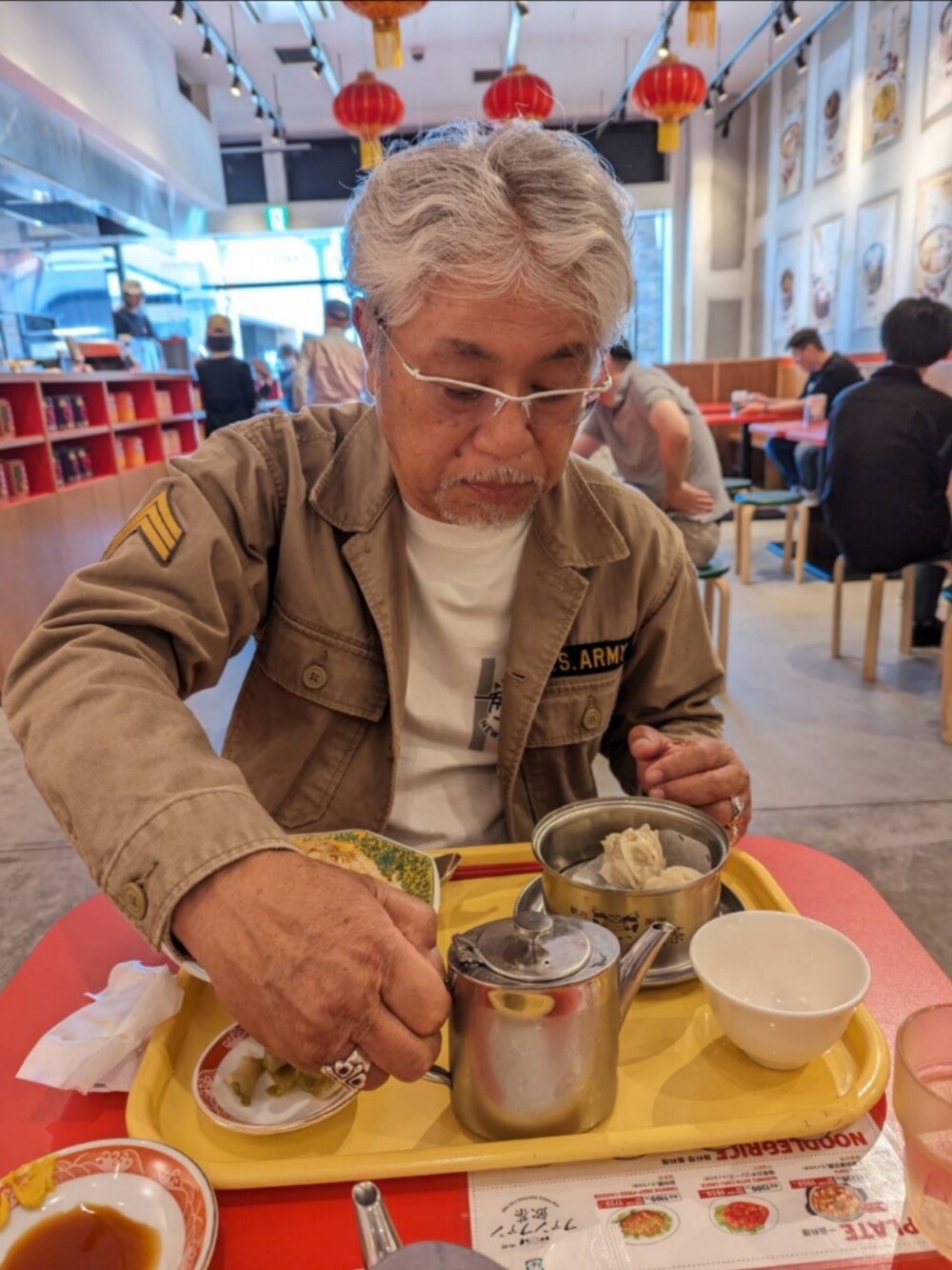 ベージュ系のミリタリージャケット、ホワイト系のTシャツ/カットソー、ブルー系のデニムパンツを着用したメンズの春コーディネートの2枚目の写真