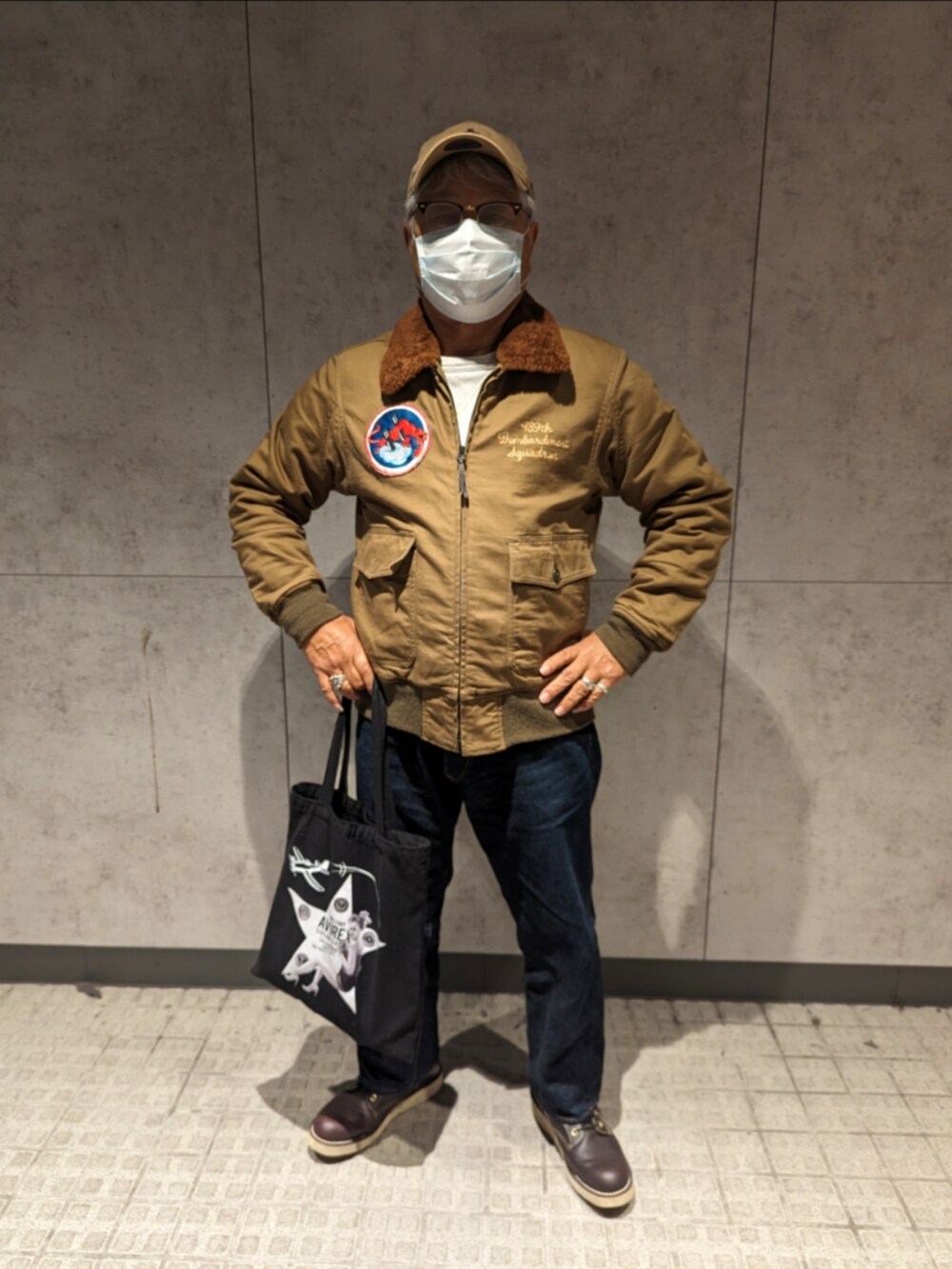 ベージュ系のミリタリージャケット、ホワイト系のスウェット、ブルー系のデニムパンツを着用したメンズの冬コーディネートの3枚目の写真