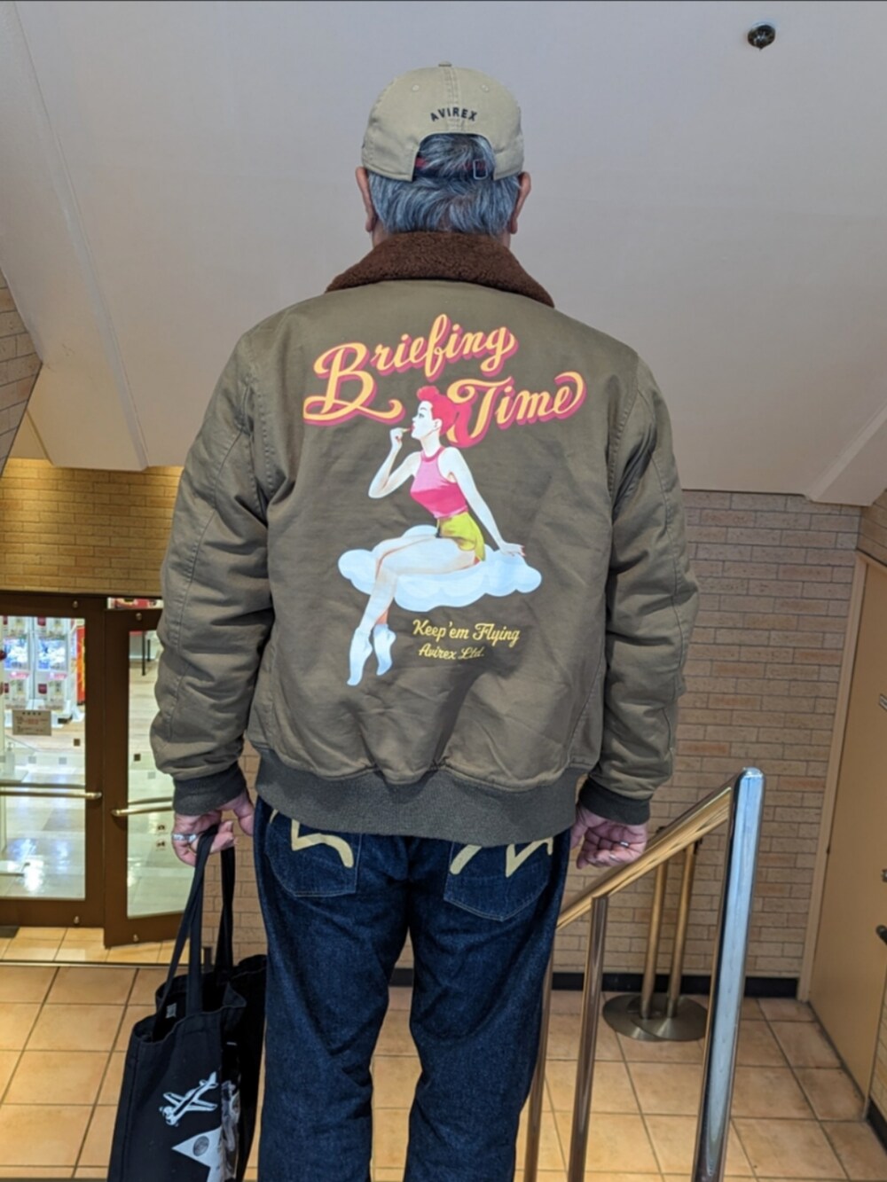 ベージュ系のミリタリージャケット、ホワイト系のスウェット、ブルー系のデニムパンツを着用したメンズの冬コーディネートの4枚目の写真