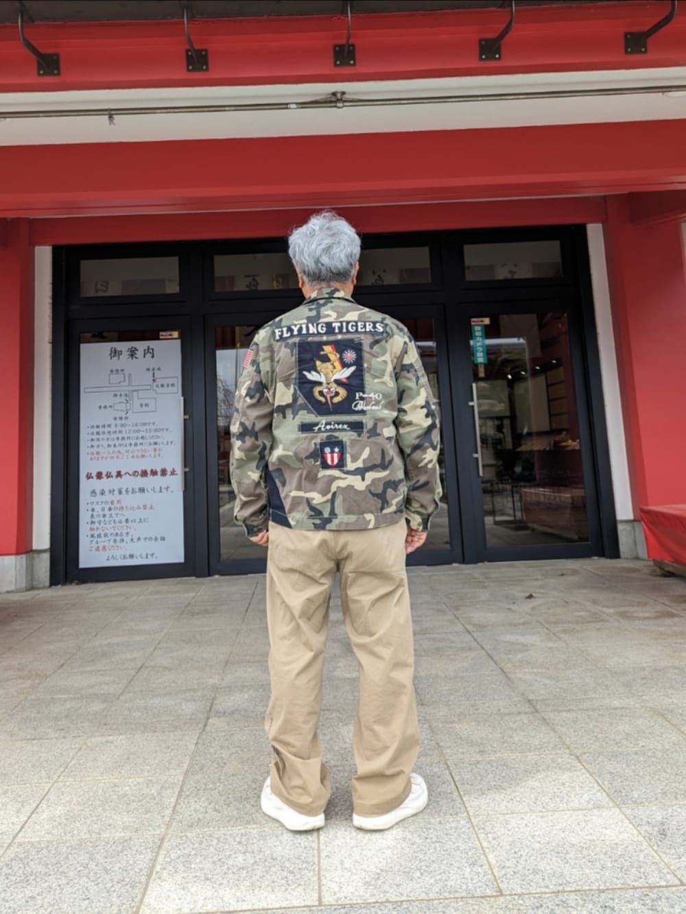 グリーン系のミリタリージャケット、ホワイト系のスウェット、ベージュ系のチノパンツを着用したメンズの春コーディネートの2枚目の写真