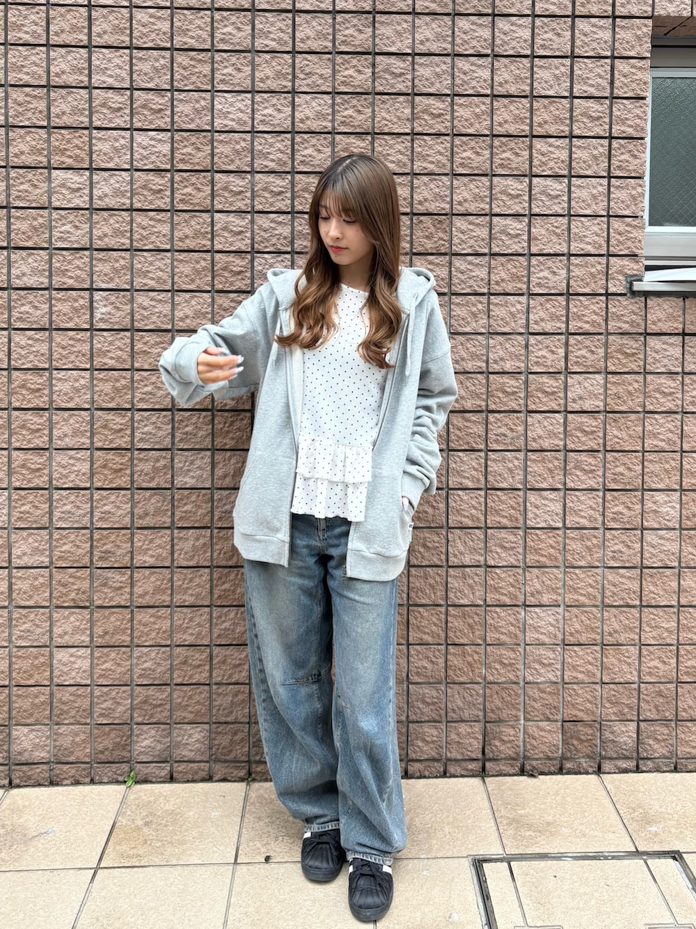 グレー系のパーカー、ブラック系のスニーカーを着用したレディースの春コーディネートの2枚目の写真