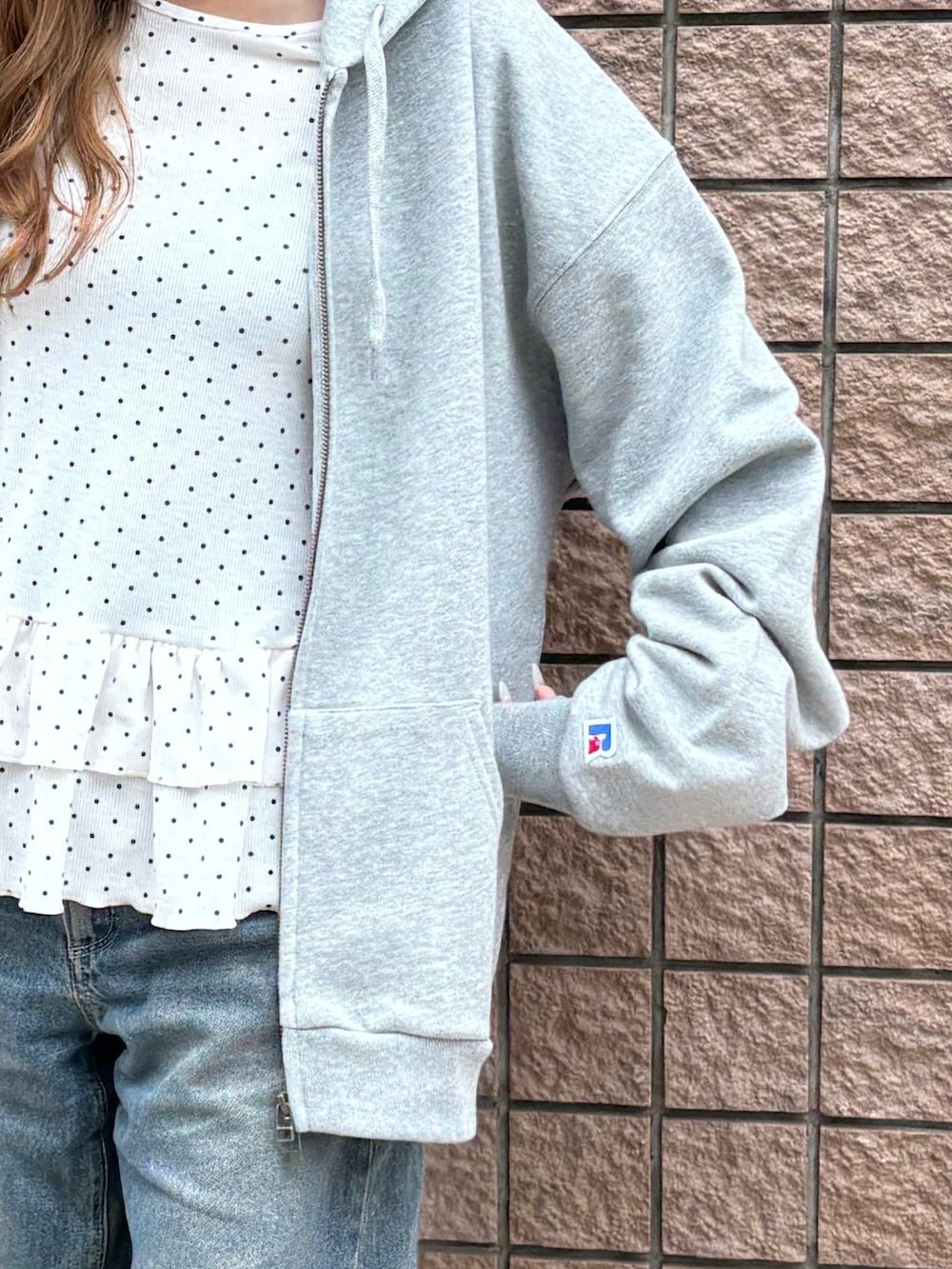 グレー系のパーカー、ブラック系のスニーカーを着用したレディースの春コーディネートの3枚目の写真