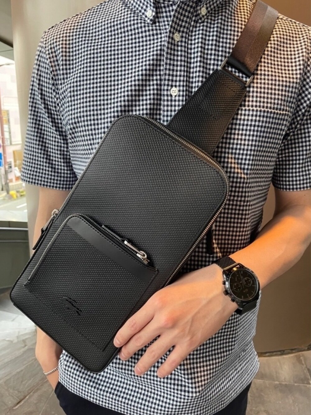 ブラック系のショルダーバッグ、ブルー系のチノパンツ、ホワイト系のスニーカーを着用したメンズの秋コーディネートの6枚目の写真