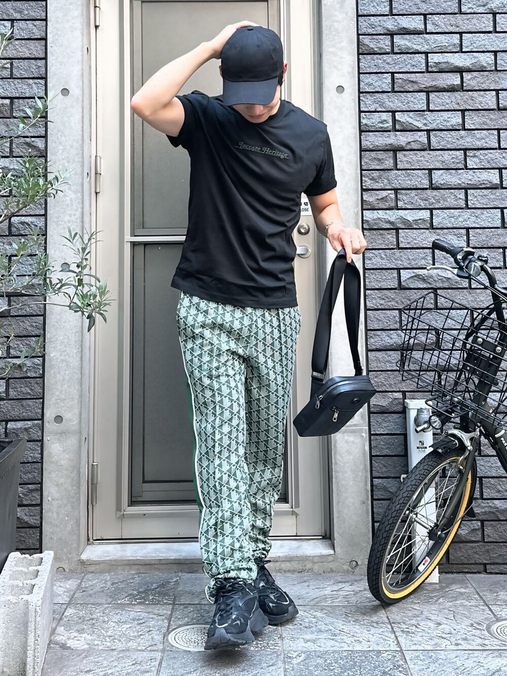 ブラック系のTシャツ/カットソー、グリーン系のスウェットパンツ、ブラック系のショルダーバッグを着用したメンズの秋コーディネートの4枚目の写真