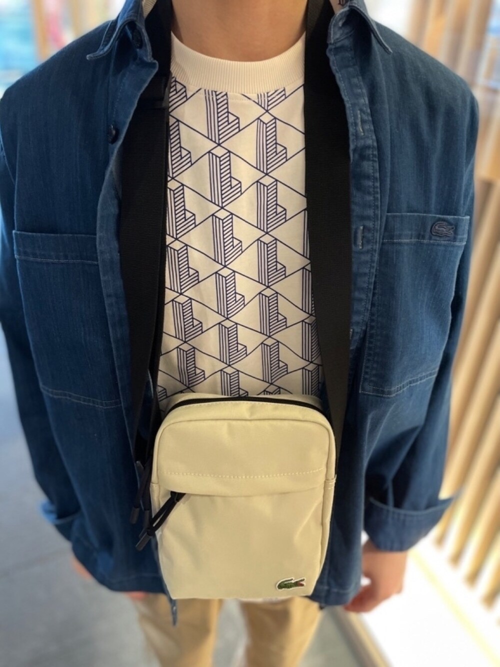 ホワイト系のTシャツ/カットソー、ホワイト系のスニーカー、ベージュ系のショルダーバッグを着用したメンズの秋コーディネートの4枚目の写真