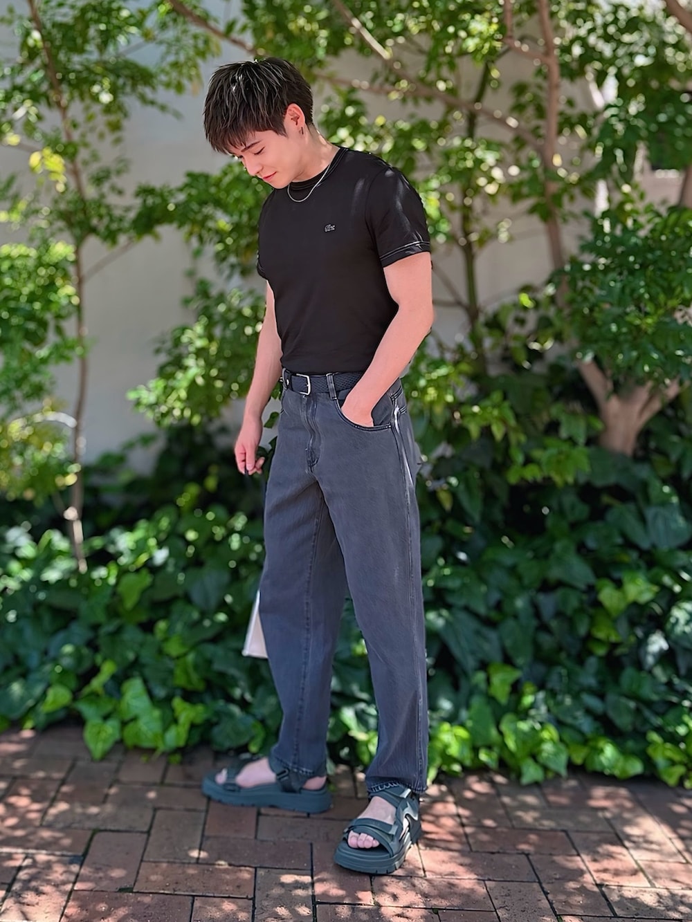 ブラック系のTシャツ/カットソー、ブラック系のデニムパンツ、ブラック系のクラッチバッグを着用したメンズの夏コーディネートの3枚目の写真