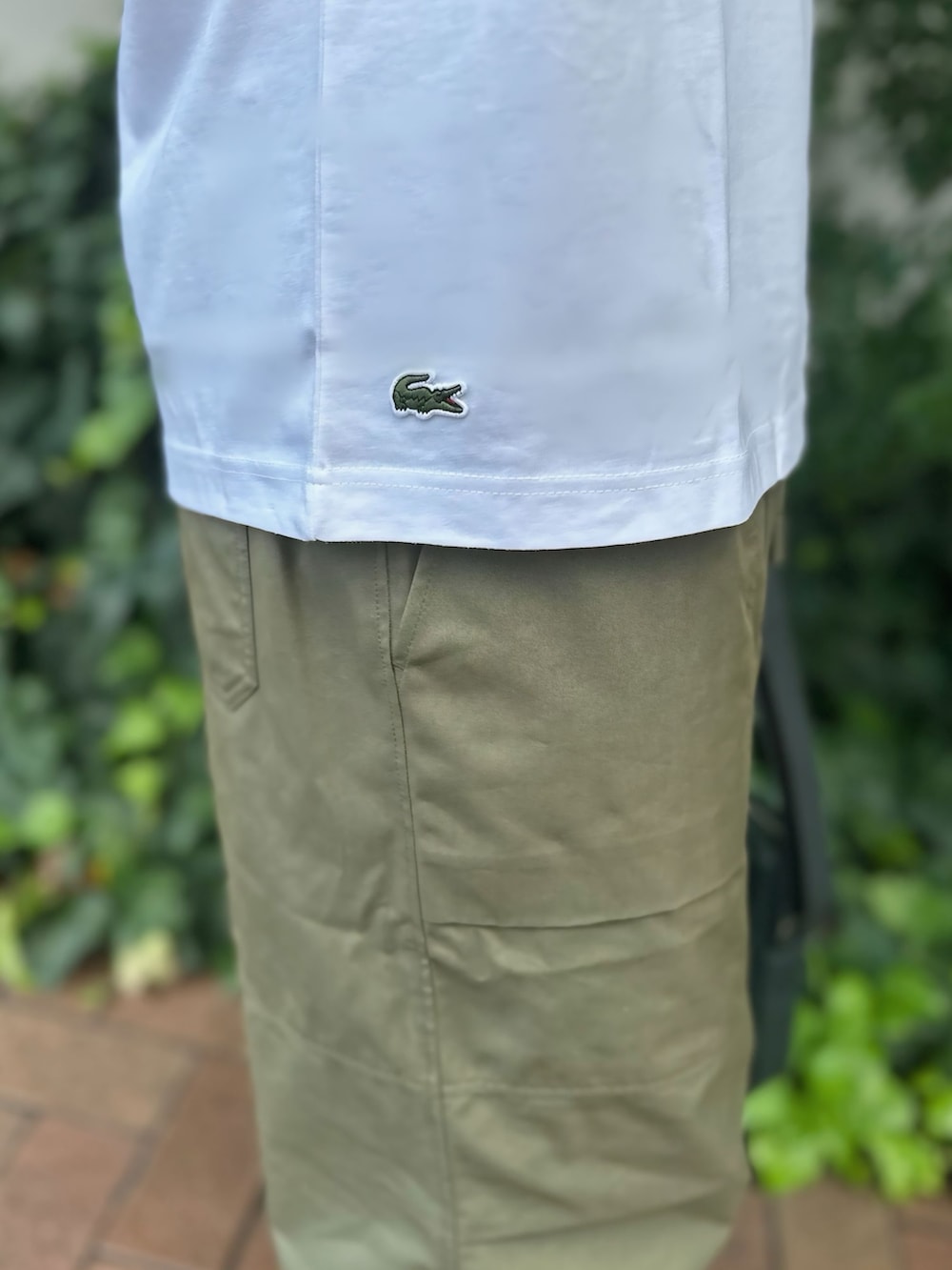 ホワイト系のTシャツ/カットソー、グリーン系のショルダーバッグ、ホワイト系のスニーカーを着用したメンズの秋コーディネートの6枚目の写真