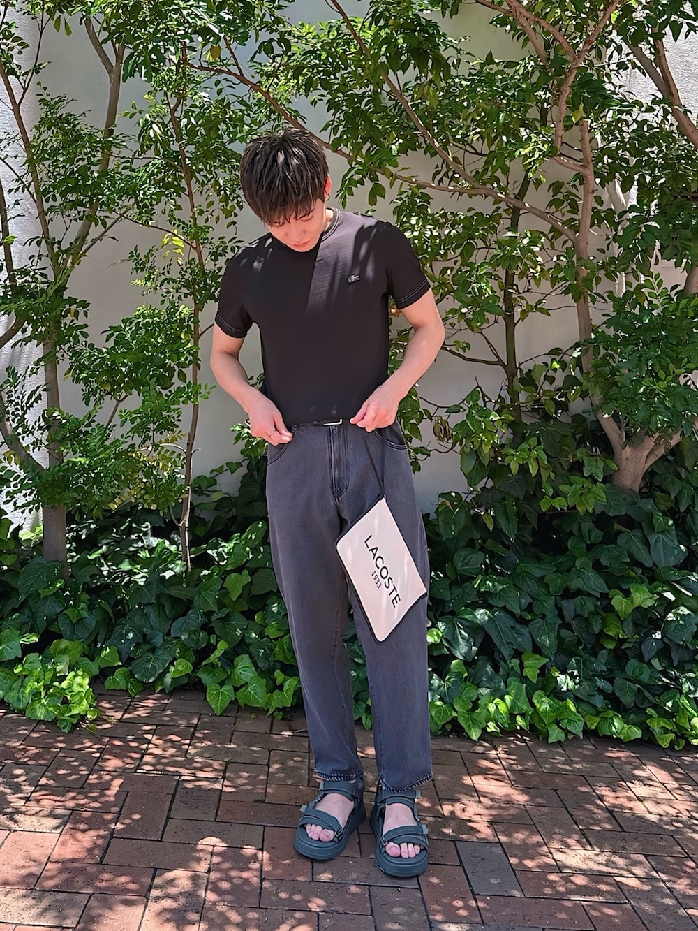 ブラック系のTシャツ/カットソー、ブラック系のデニムパンツ、ブラック系のクラッチバッグを着用したメンズの夏コーディネートの2枚目の写真