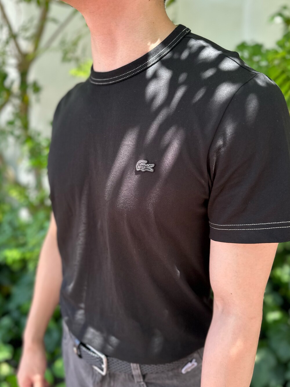 ブラック系のTシャツ/カットソー、ブラック系のデニムパンツ、ブラック系のクラッチバッグを着用したメンズの夏コーディネートの7枚目の写真