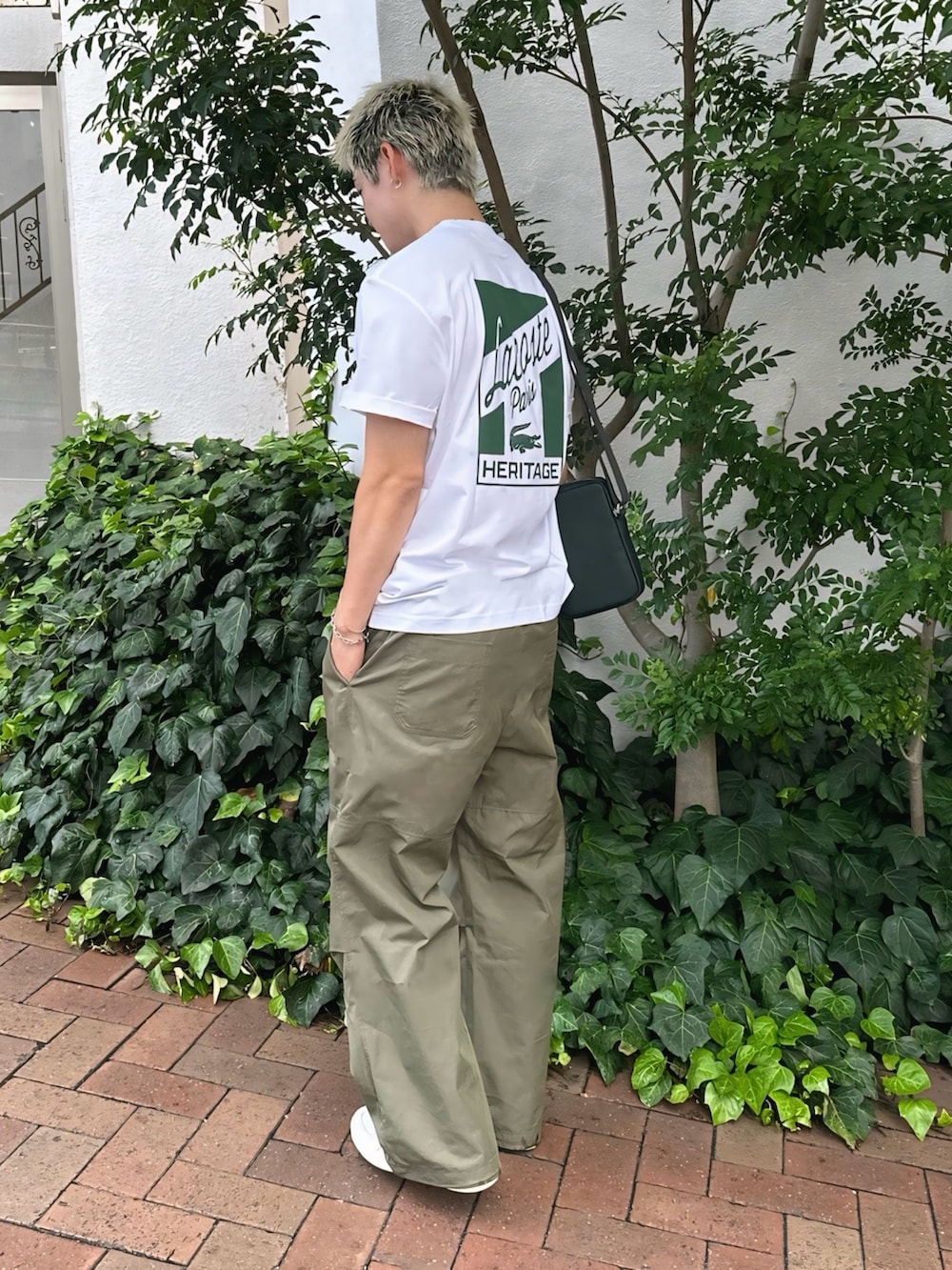 ホワイト系のTシャツ/カットソー、グリーン系のショルダーバッグ、ホワイト系のスニーカーを着用したメンズの秋コーディネートの3枚目の写真