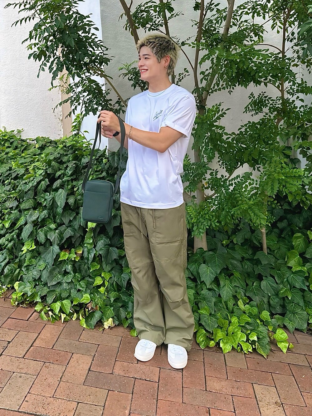 ホワイト系のTシャツ/カットソー、グリーン系のショルダーバッグ、ホワイト系のスニーカーを着用したメンズの秋コーディネートの2枚目の写真