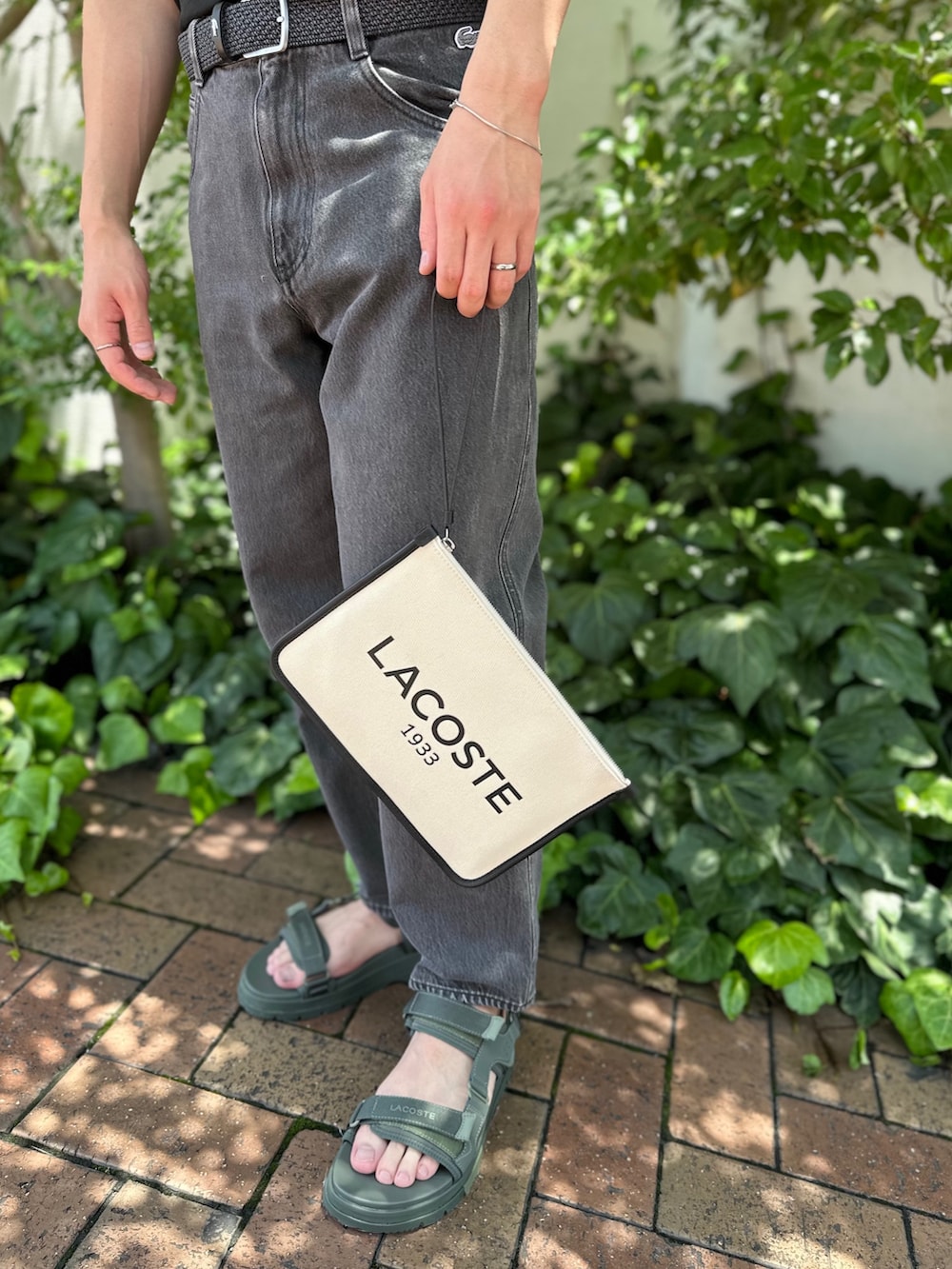 ブラック系のTシャツ/カットソー、ブラック系のデニムパンツ、ブラック系のクラッチバッグを着用したメンズの夏コーディネートの5枚目の写真