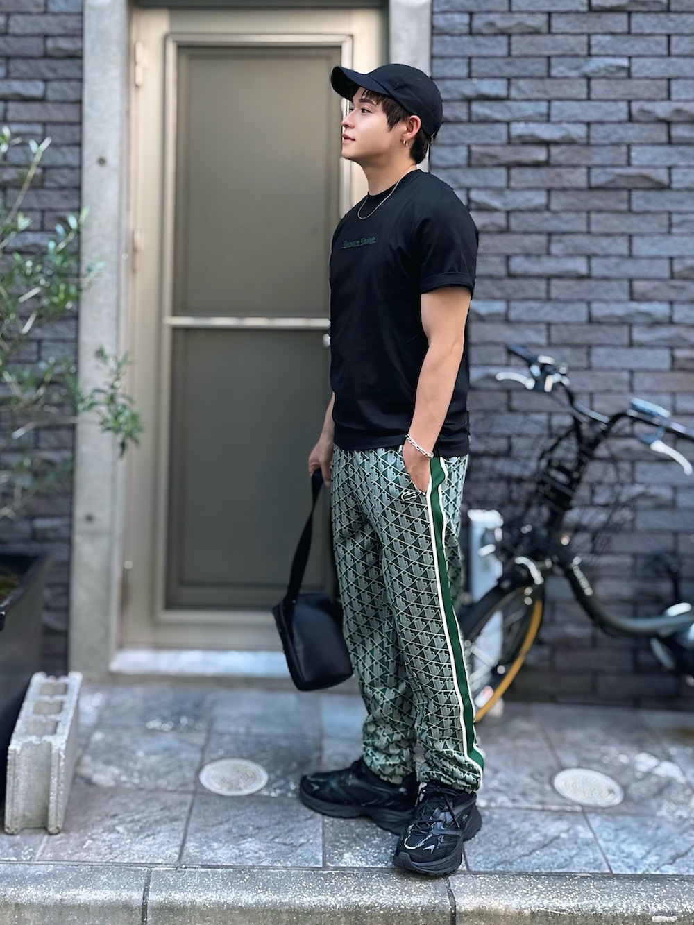 ブラック系のTシャツ/カットソー、グリーン系のスウェットパンツ、ブラック系のショルダーバッグを着用したメンズの秋コーディネートの2枚目の写真
