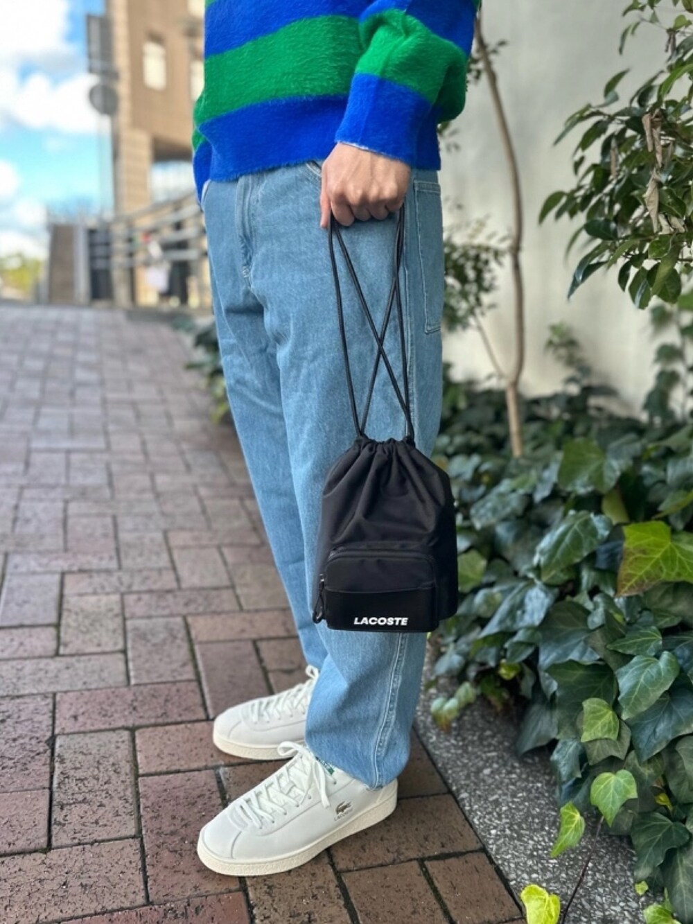 ブルー系のニット/セーター、グレー系のデニムパンツ、ホワイト系のスニーカーを着用したメンズの春コーディネートの4枚目の写真