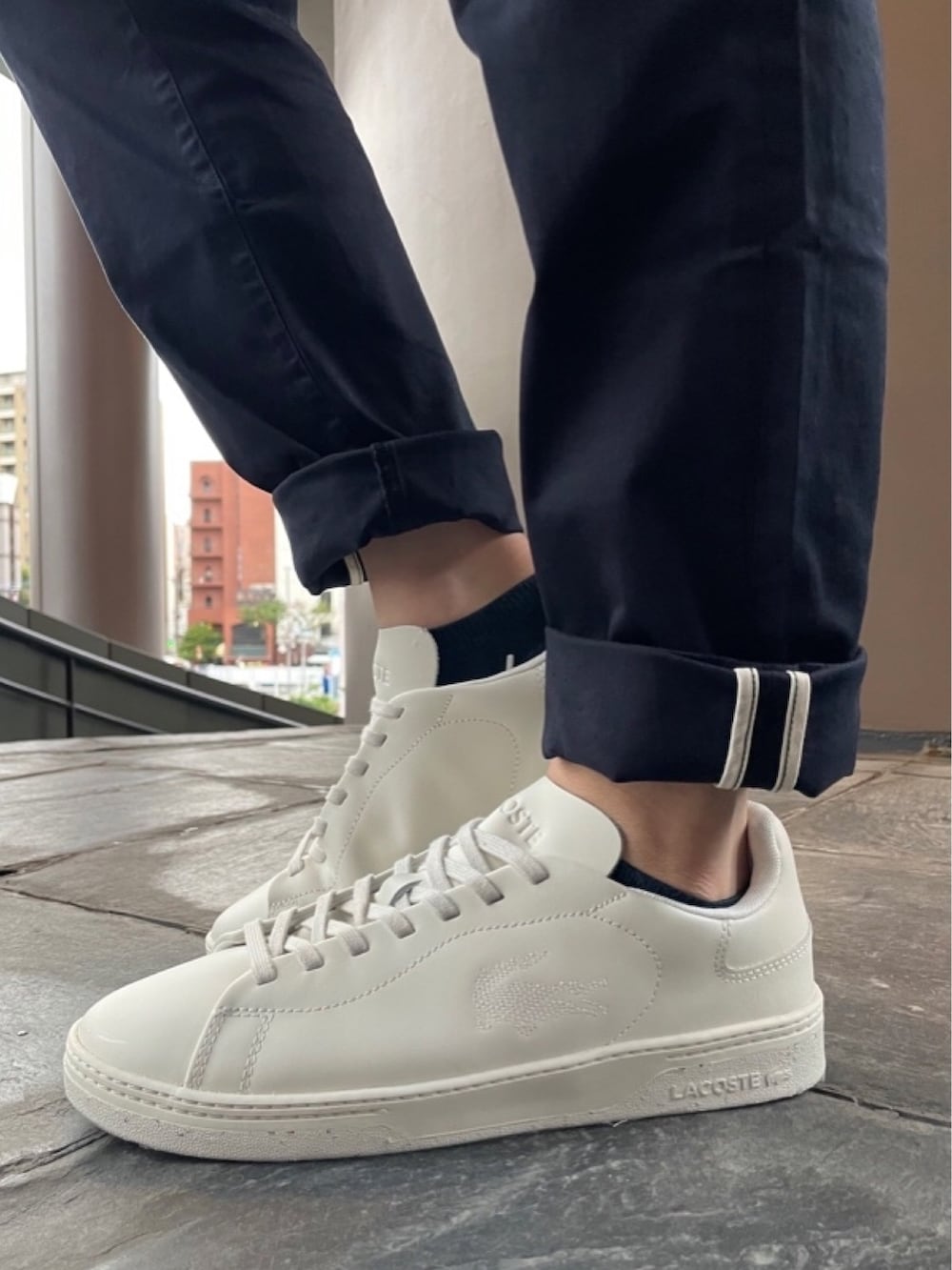 ブラック系のショルダーバッグ、ブルー系のチノパンツ、ホワイト系のスニーカーを着用したメンズの秋コーディネートの7枚目の写真