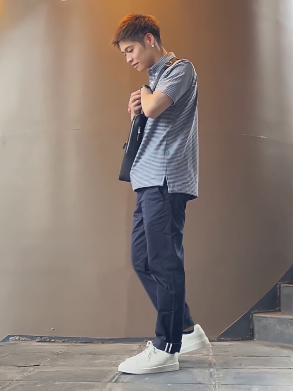 ブラック系のショルダーバッグ、ブルー系のチノパンツ、ホワイト系のスニーカーを着用したメンズの秋コーディネートの2枚目の写真