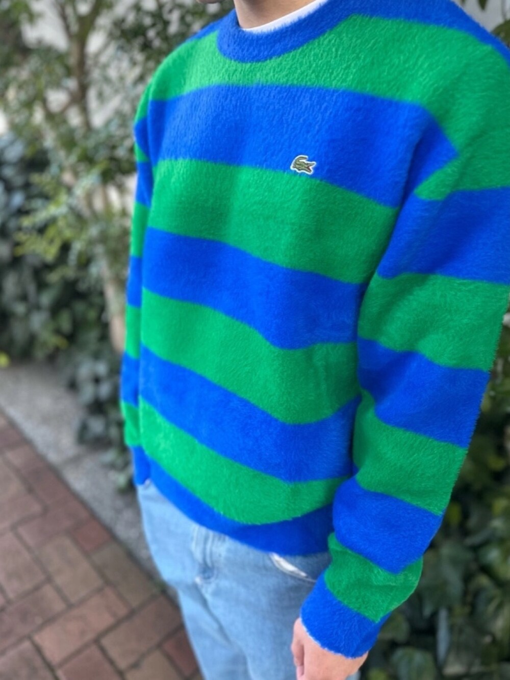 ブルー系のニット/セーター、グレー系のデニムパンツ、ホワイト系のスニーカーを着用したメンズの春コーディネートの3枚目の写真