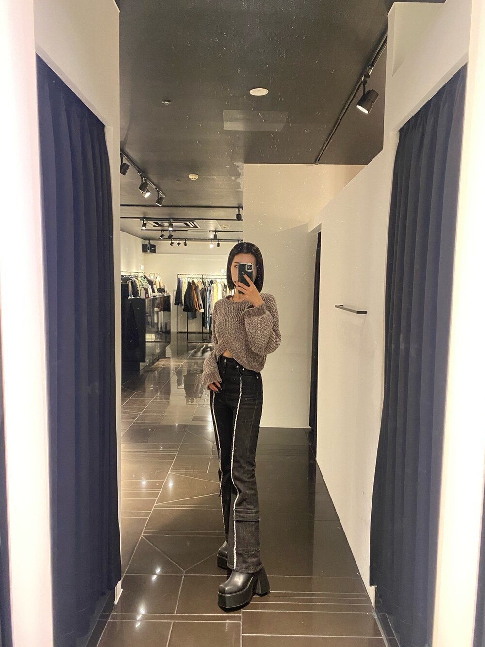 グレー系のニット/セーター、ブラック系のデニムパンツ、ブラック系のブーツを着用したレディースの秋コーディネートの2枚目の写真