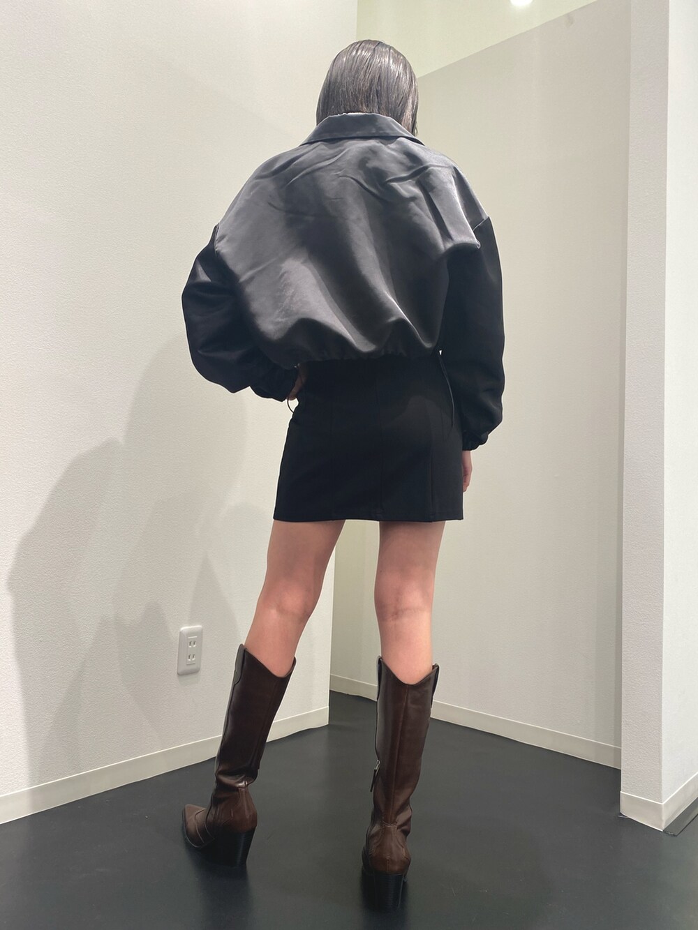 ブラック系のブルゾン、ブラック系のスカート、ブラウン系のブーツを着用したレディースの春コーディネートの2枚目の写真