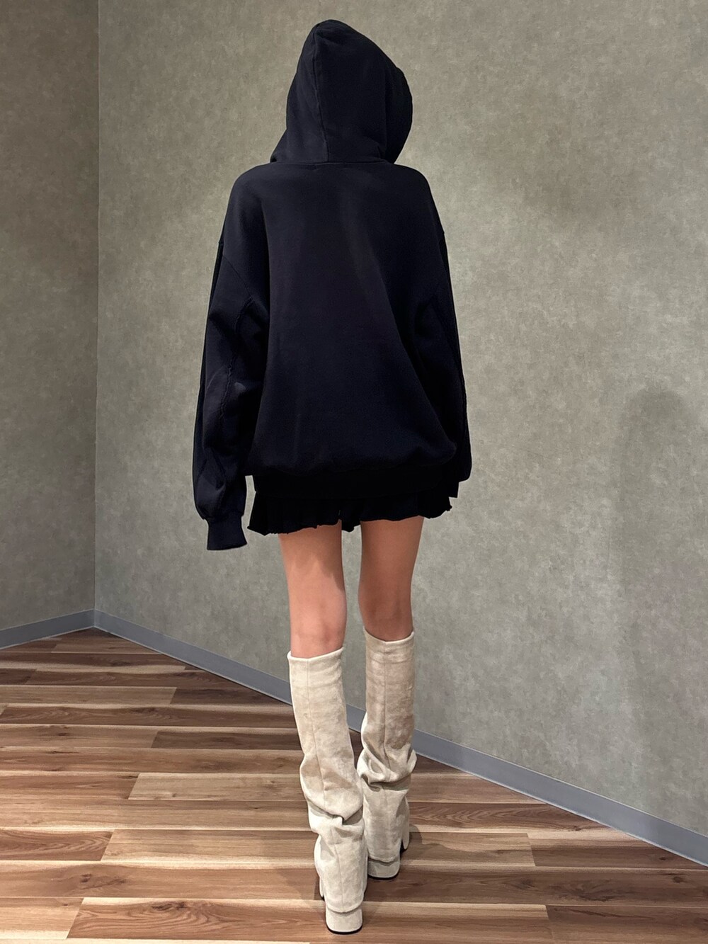 ホワイト系のブーツ、ブラック系のスカート、ブラック系のパーカーを着用したレディースの秋コーディネートの3枚目の写真