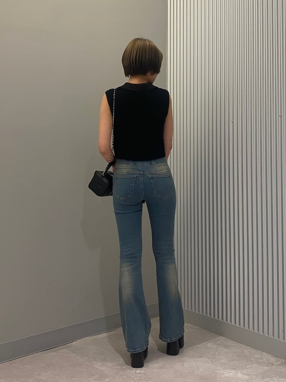 ブラック系のハンドバッグ、ブラック系のタンクトップ、ブルー系のデニムパンツを着用したレディースの夏コーディネートの3枚目の写真