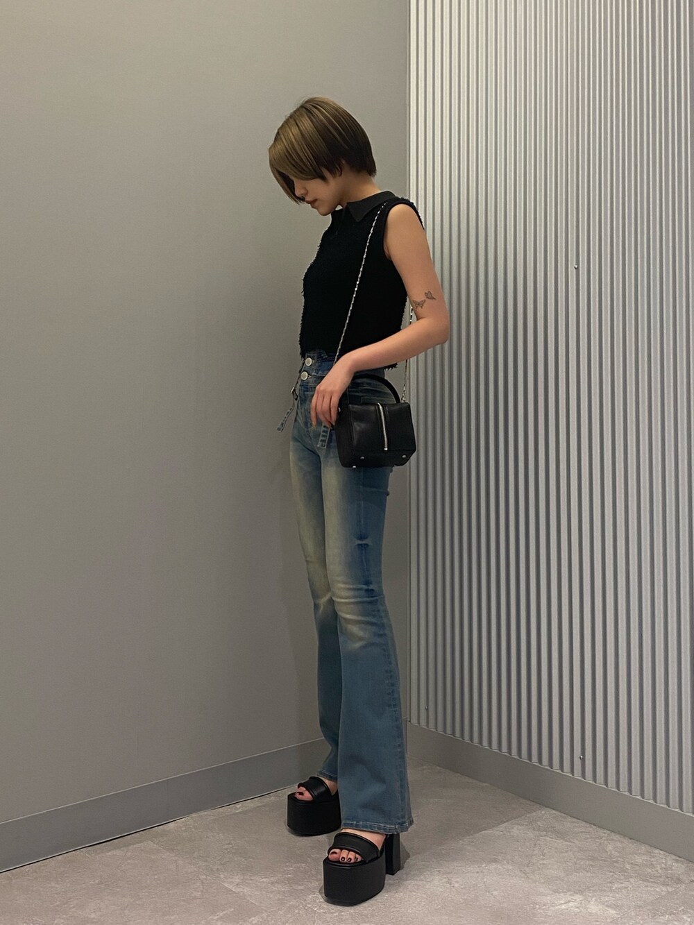 ブラック系のハンドバッグ、ブラック系のタンクトップ、ブルー系のデニムパンツを着用したレディースの夏コーディネートの2枚目の写真