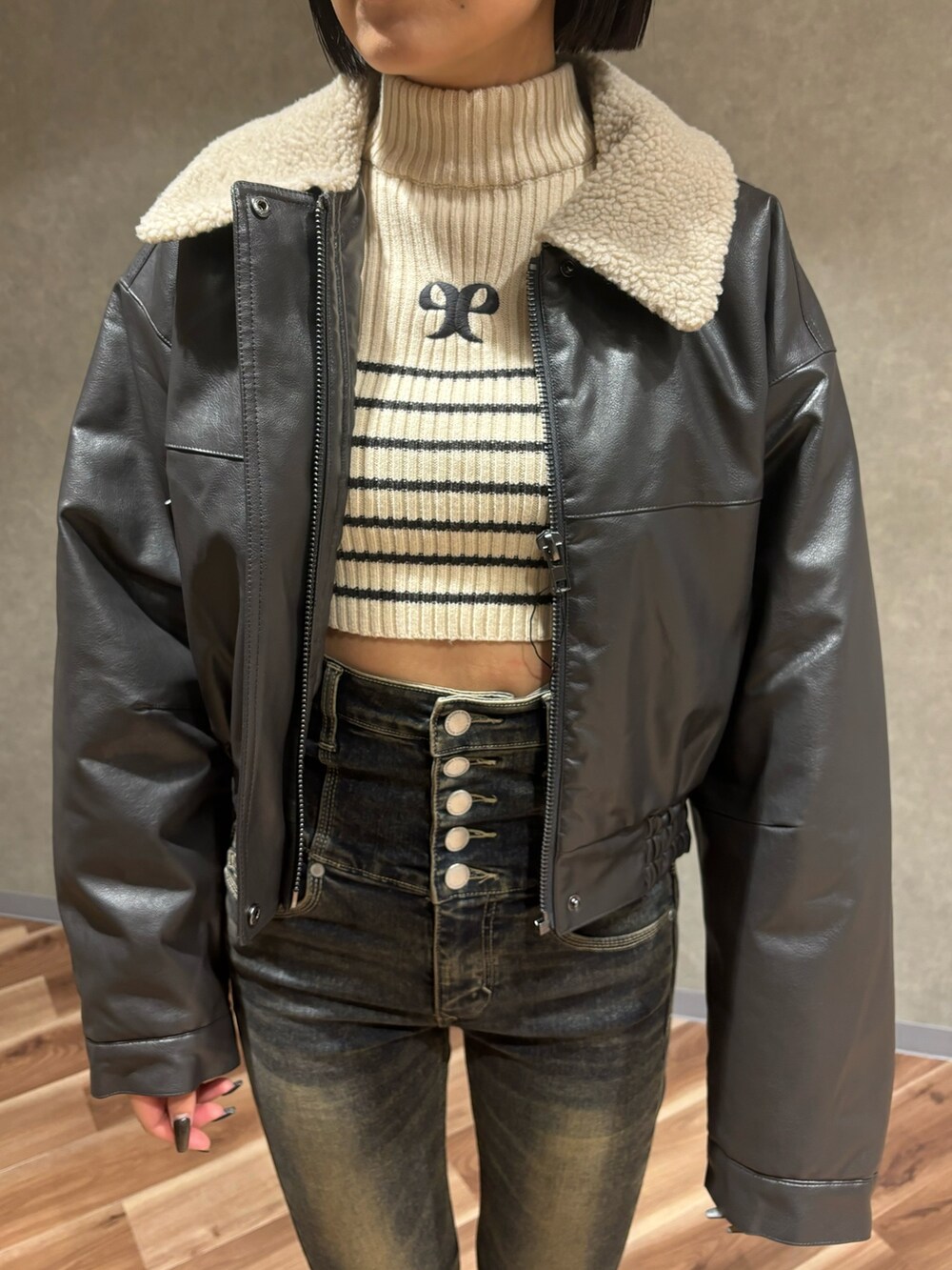 グレー系のブルゾン、ホワイト系のニット/セーター、ブルー系のデニムパンツを着用したレディースの秋コーディネートの4枚目の写真