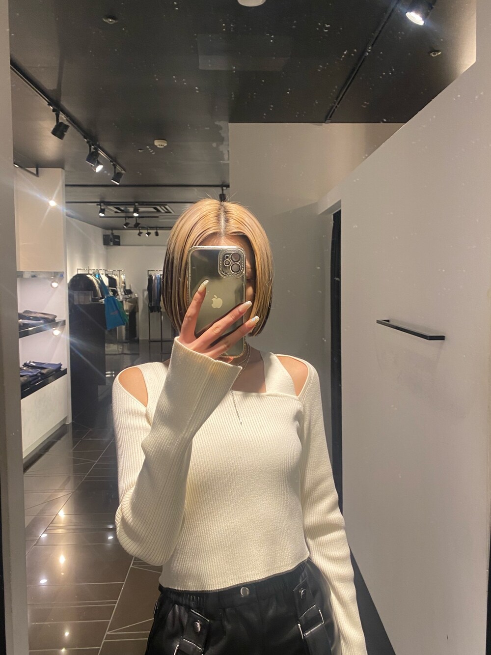 ブラック系のブーツ、ブラック系のスカート、ホワイト系のニット/セーターを着用したレディースの冬コーディネートの5枚目の写真