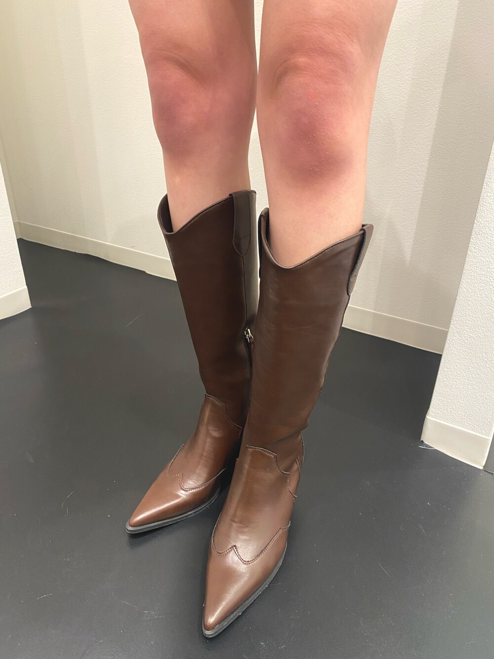 ブラック系のブルゾン、ブラック系のスカート、ブラウン系のブーツを着用したレディースの春コーディネートの5枚目の写真