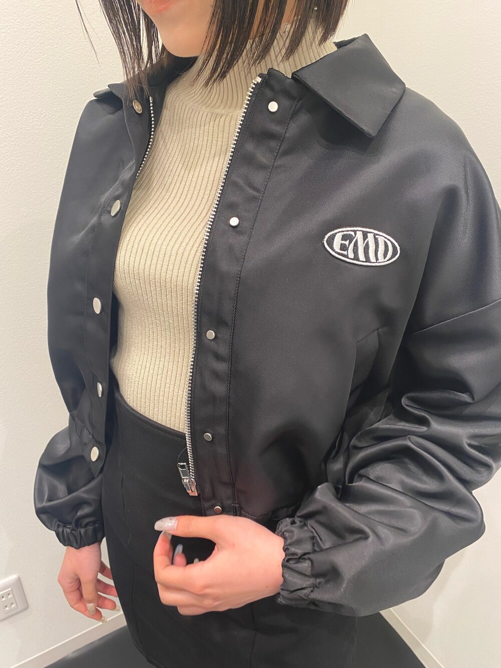 ブラック系のブルゾン、ブラック系のスカート、ブラウン系のブーツを着用したレディースの春コーディネートの4枚目の写真