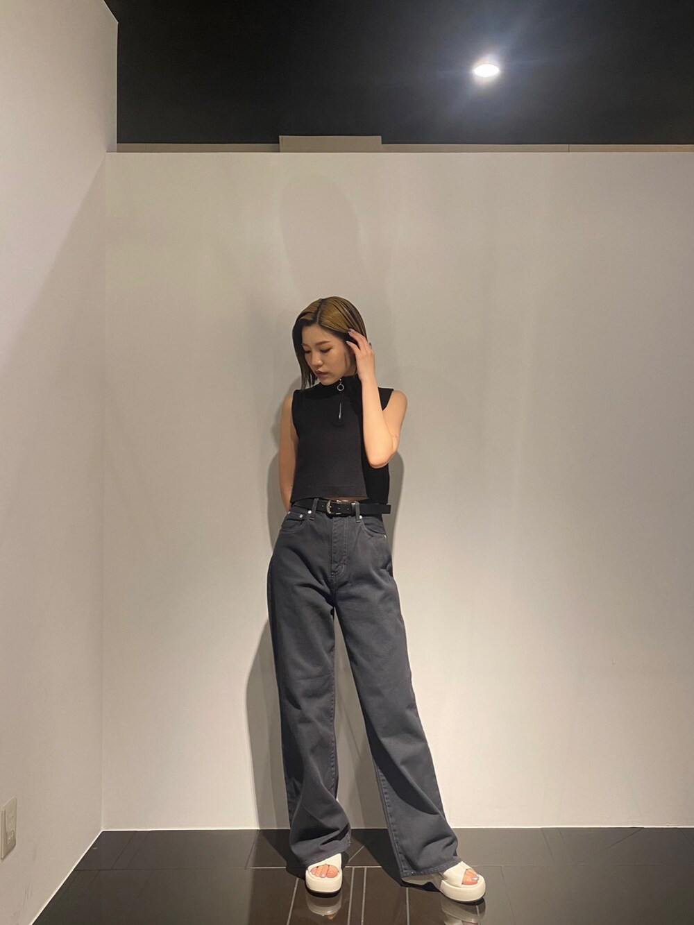 ブラック系のデニムパンツ、ホワイト系のサンダル、ブラック系のタンクトップを着用したレディースの春コーディネートの2枚目の写真