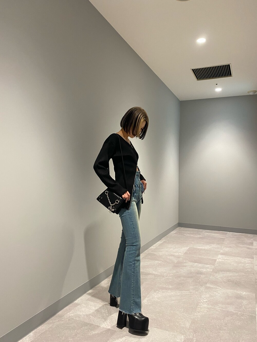 ブルー系のデニムパンツ、ブラック系のショルダーバッグ、ブラック系のブーツを着用したレディースの冬コーディネートの2枚目の写真