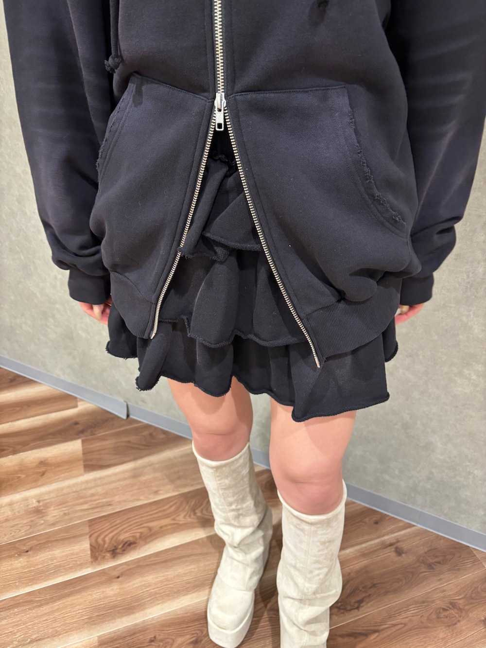 ホワイト系のブーツ、ブラック系のスカート、ブラック系のパーカーを着用したレディースの秋コーディネートの4枚目の写真