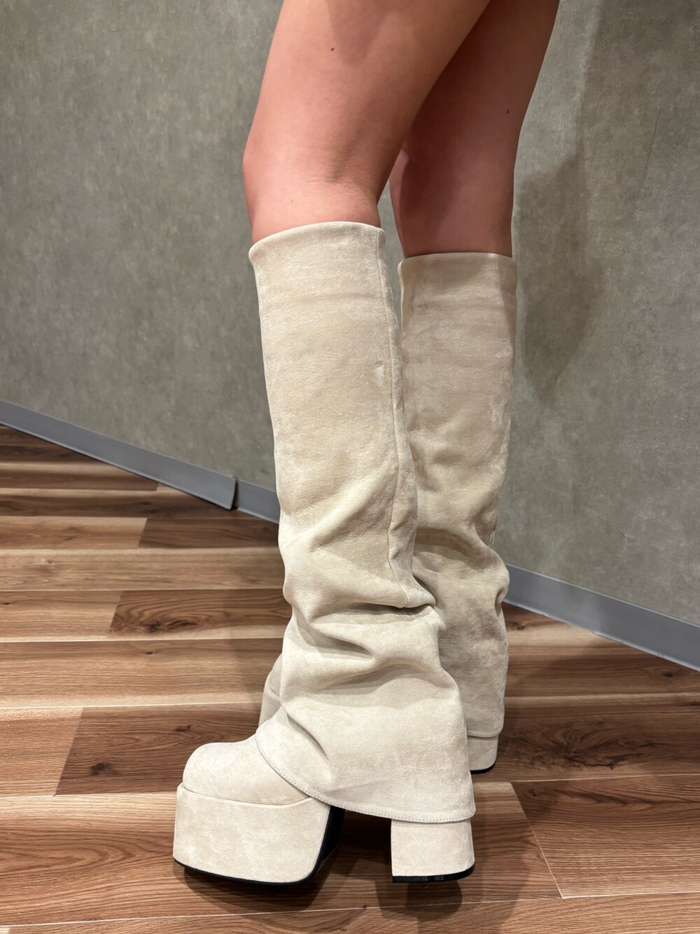 ホワイト系のブーツ、ブラック系のスカート、ブラック系のパーカーを着用したレディースの秋コーディネートの5枚目の写真