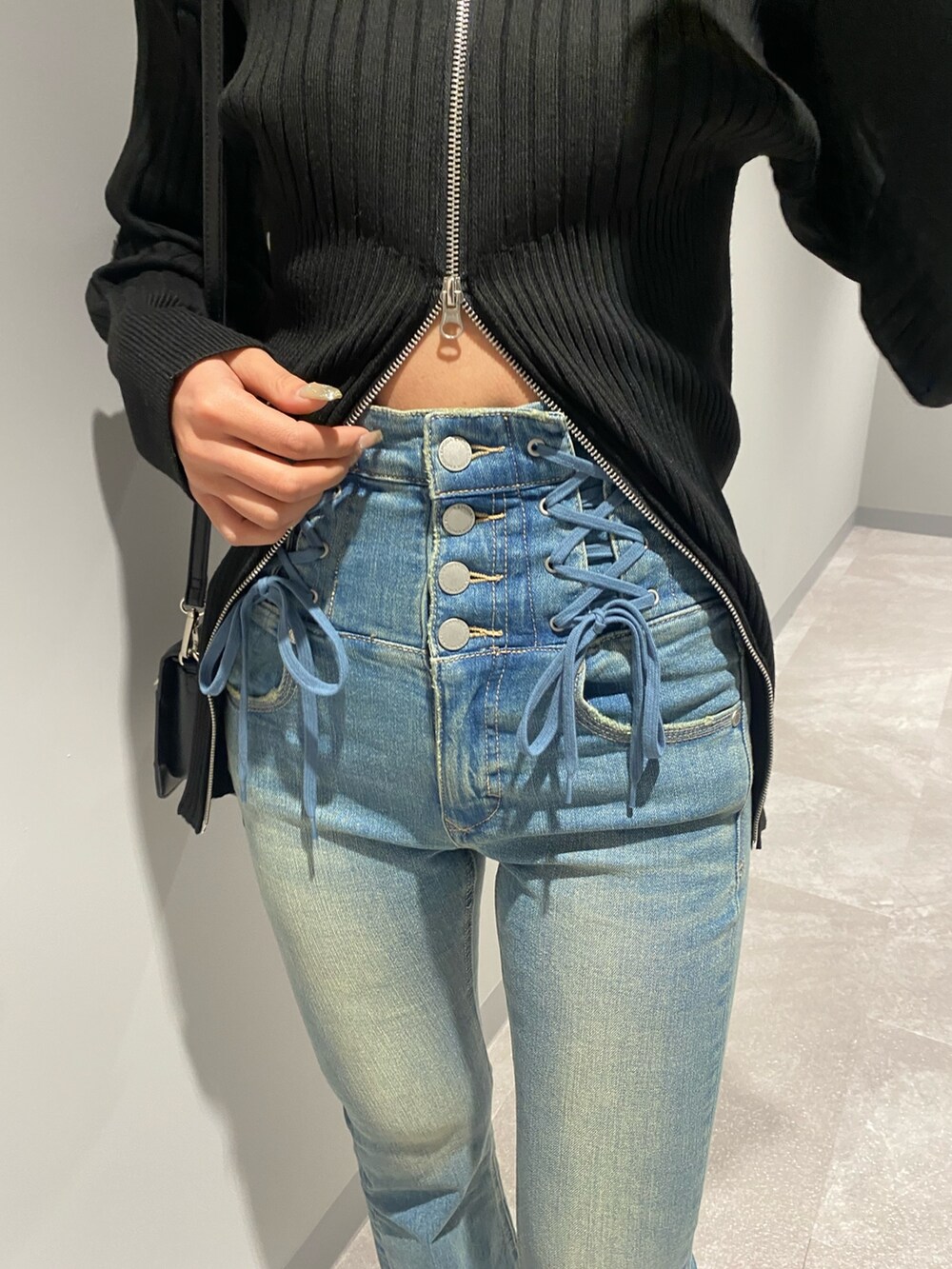 ブルー系のデニムパンツ、ブラック系のショルダーバッグ、ブラック系のブーツを着用したレディースの冬コーディネートの4枚目の写真