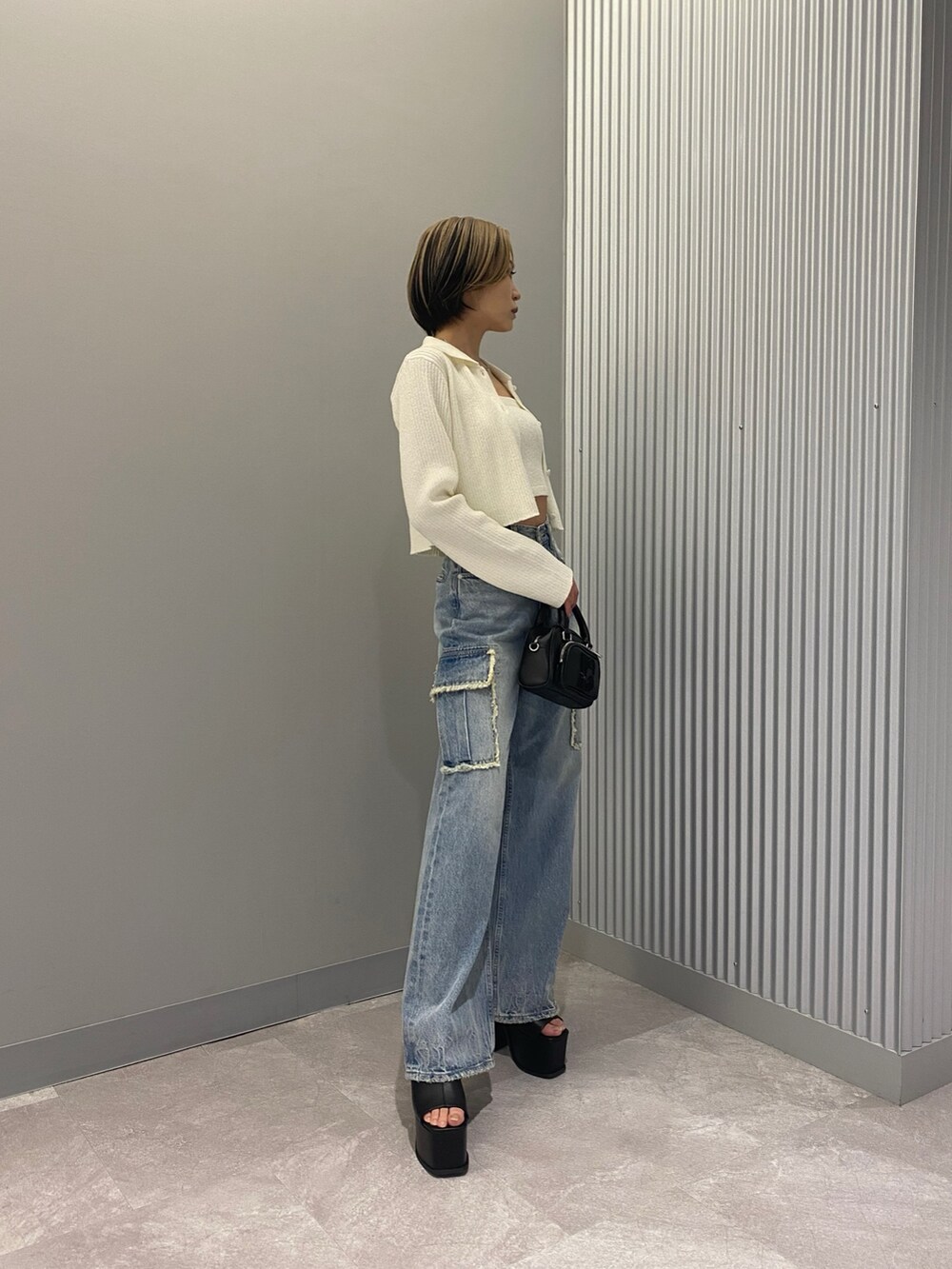 ホワイト系のニット/セーター、ブルー系のデニムパンツ、ブラック系のサンダルを着用したレディースの春コーディネートの2枚目の写真