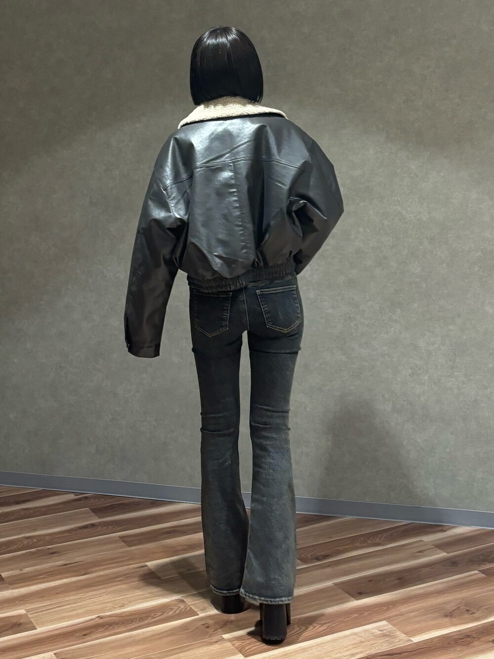 グレー系のブルゾン、ホワイト系のニット/セーター、ブルー系のデニムパンツを着用したレディースの秋コーディネートの3枚目の写真